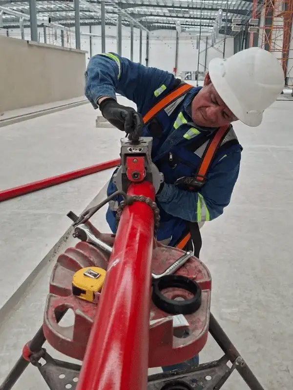 Técnico instalando tubería de red hidráulica contra incendios en nave industrial