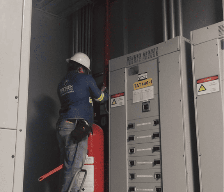 Técnico de FireTech Solutions verificando sistema contra incendios de supresión especial en cuarto técnico
