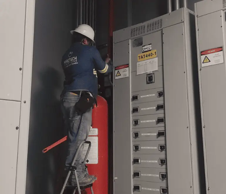 Técnico de FireTech Solutions verificando sistema contra incendios en cuarto técnico