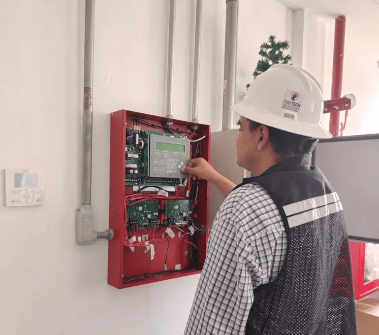 Técnico de FireTech Solutions programando tablero de alarma contra incendio