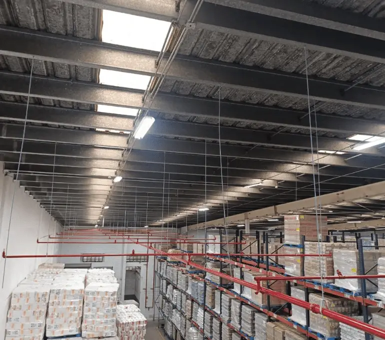Instalación terminada de sistema de rociadores automáticos instalado sobre racks de almacenamiento en centro de distribución