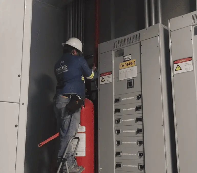 Técnico de FireTech Solutions durante la instalación de sistemas contra incendios en cuarto eléctrico
