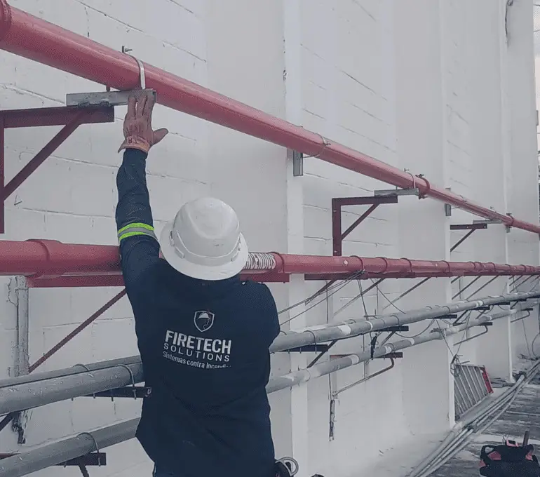 Técnico de FireTech Solutions instalando red hidráulica contra incendio en fachada exterior