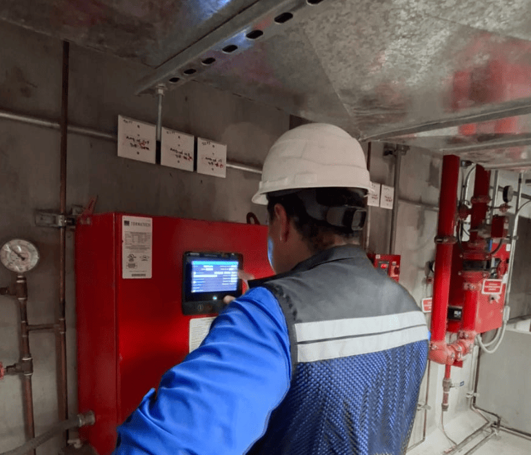Técnico revisando controlador de bomba contra incendio durante mantenimiento